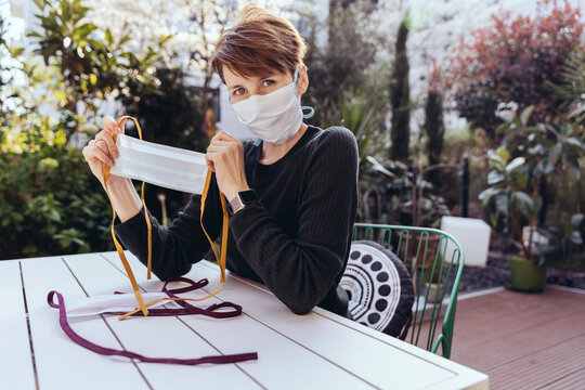 Woman sitting in garden, showing self-made face masks