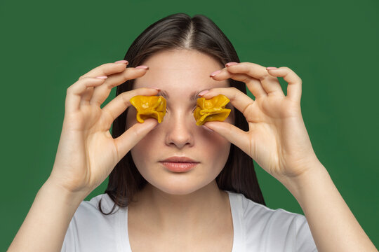Portrait of young woman covering eyes with tortellini