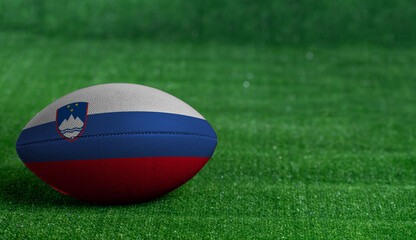 Fototapeta na wymiar American football ball with Slovenia flag on green grass background, close up