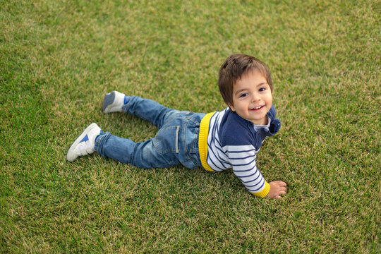 Portrait of smiling little boy lying on lawn