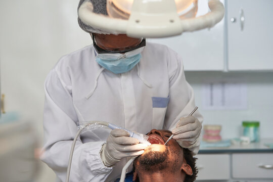 Female dentist cleaning teeth of a man