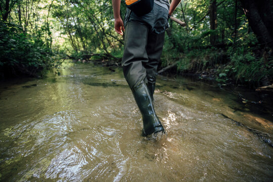 Back view of young angler wading in water, partial view