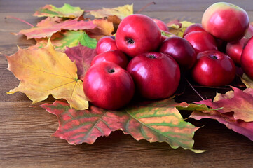 Autumn composition of red apples and yellow maple leaves lying on wooden table. Harvest time. Colorful nature