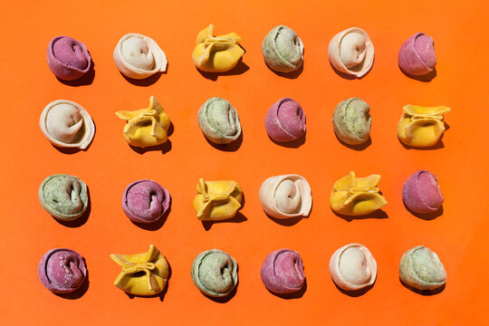 Rows of various tortellini on orange background