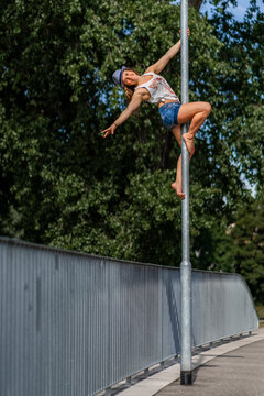 Smiling young woman climbing up a lamppost