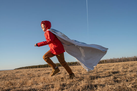 Boy dressed up as superhero running in steppe landscape