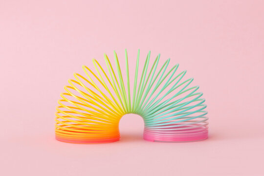 Rainbow plastic spring toy on pink background