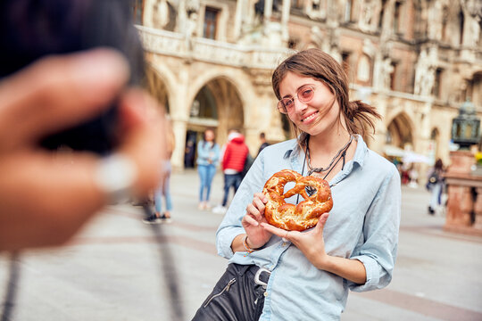 Young couple taking a photo, woman with brezel in Munich, Germany