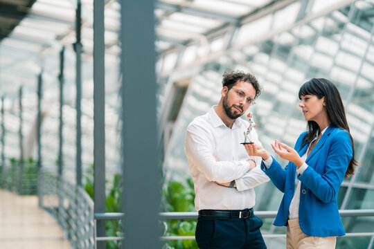 Businesswoman explaining male colleague about robot model in office corridor