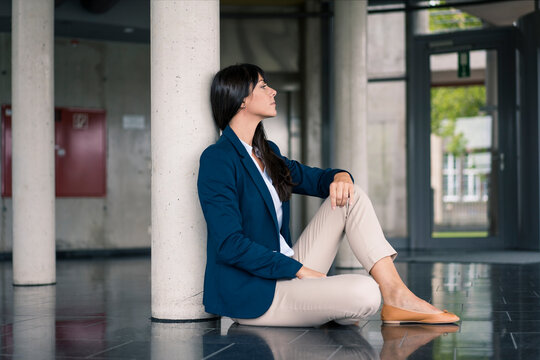 Businesswoman contemplating while sitting by column in office lobby
