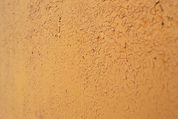 A peeling layer of orange paint on the wall. Background with peeling orange paint