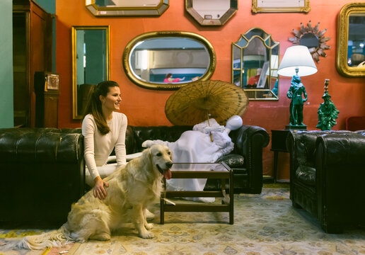 Smiling woman with dog sitting on couch in a vintage shop