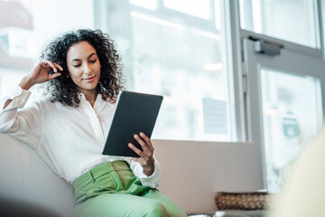 Young businesswoman using digital tablet while sitting at cafe