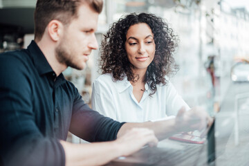 Business people with laptop having discussion while sitting at cafe