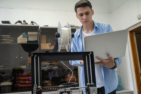 Student setting up 3D printer, using laptop
