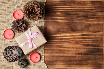 Christmas Flatlay of pine cones, candles and gift boxes on wooden background with copy space