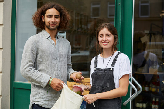 Portrait of smiling man and woman standing at entrance door of a store