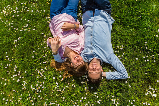 Happy young couple relaxing on grass in a park, overhead view
