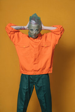 Portrait of young woman wearing orange jacket in front of yellow background
