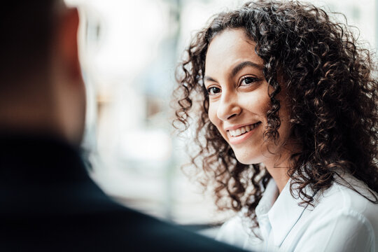 Smiling businesswoman looking at colleague while sitting at cafe