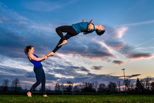 Young couple doing acrobatics at sunset