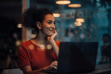 Thoughtful woman with laptop looking away while sitting at cafe