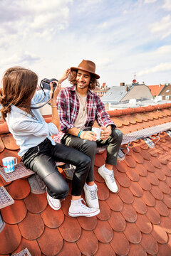 Young couple sitting on rooftop and taking a picture