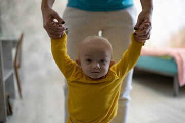 Fototapeta na wymiar Mother teaches little boy infant to walk