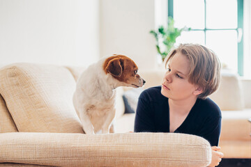 Boy with dog lying on couch in living room at home