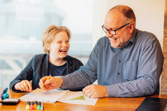 Happy father and son doing homework at desk