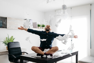 Mischievous boy playing with toilet paper on desk in home office