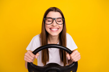 Photo of cheerful young positive joyful woman hold hands steering wheel isolated on yellow color...