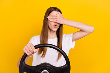 Photo of young scared young amazed woman hold hand cover eyes steering wheel isolated on yellow...