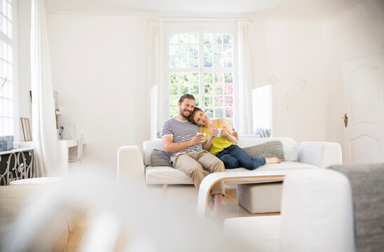 Happy young couple sitting on couch at home
