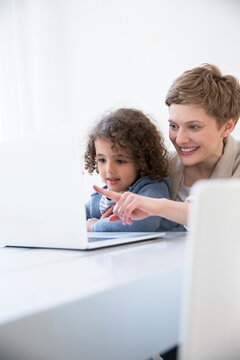 Smiling mother and son using laptop at home