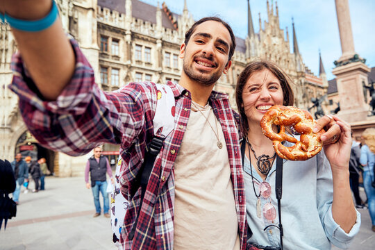 Young couple taking a selfie with brezel in Munich, Germany