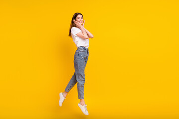 Fototapeta na wymiar Full size photo of happy positive young woman jump up hold hands face smile isolated on yellow color background
