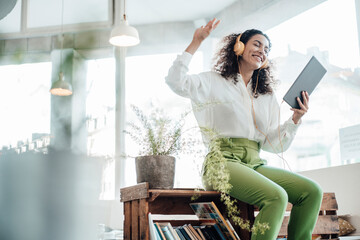 Businesswoman wearing headphones using digital tablet while sitting on table at cafe