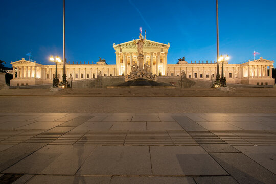 Exterior of illuminated Austrian Parliament Building in Vienna against clear blue sky at night