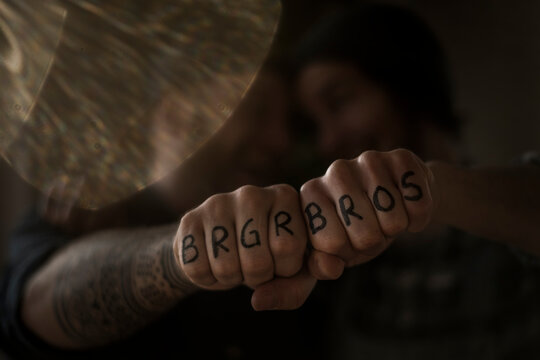 Friends holding fists together, showing their tattoos