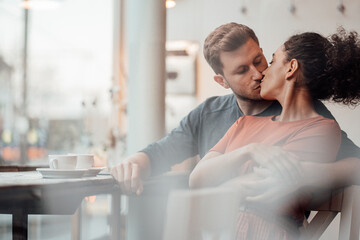 Young woman kissing man while sitting together at cafe
