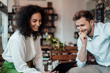 Smiling entrepreneurs using digital tablet while working at cafe