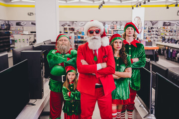 Naklejka premium Portrait of attractive content funky company elfs super hero buying goods devices folded arms December bargain at mall store indoors