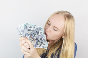 Close-up of a girl sniffing money. Madness and greed from currency. The concept of corruption and getting money at any cost. Squeeze and toss US dollars. Wild thirst for profit