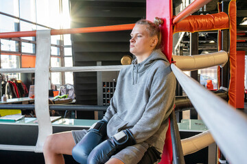Female boxer in gym sitting in ring corner