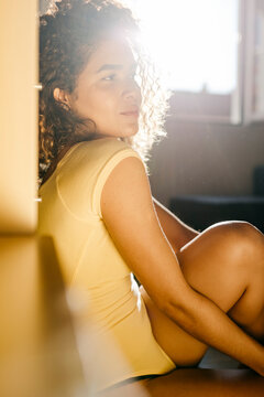 Portrait Of Attractive Young Woman Sitting On The Floor At Home In Sunlight