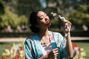 Beautiful young woman holding flower in a public garden in spring