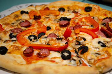 Traditional pizza with skolbaski, tomatoes, olives and cheese. Selective focus, unhealthy food concept