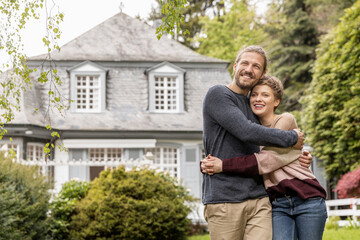 Happy young couple embracing in garden of their home