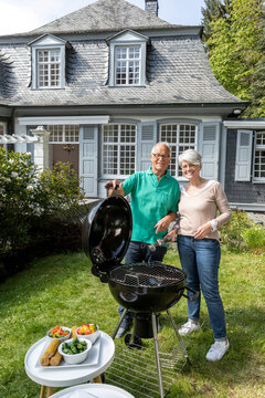 Happy senior couple having a barbecue in garden of their home